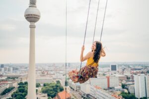 Weibliche Person sitzt auf der höchsten Schaukel Europas - High Swing Berlin.